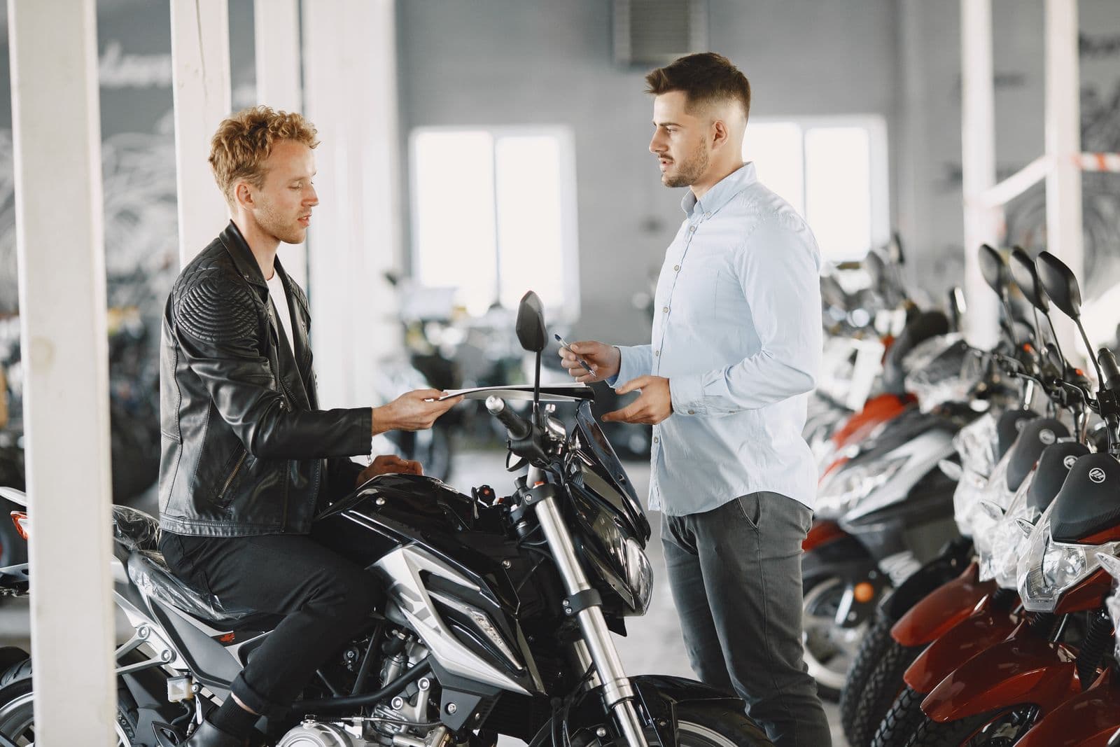 Verkoper overhandigt de sleutel aan een klant in de motorshowroom