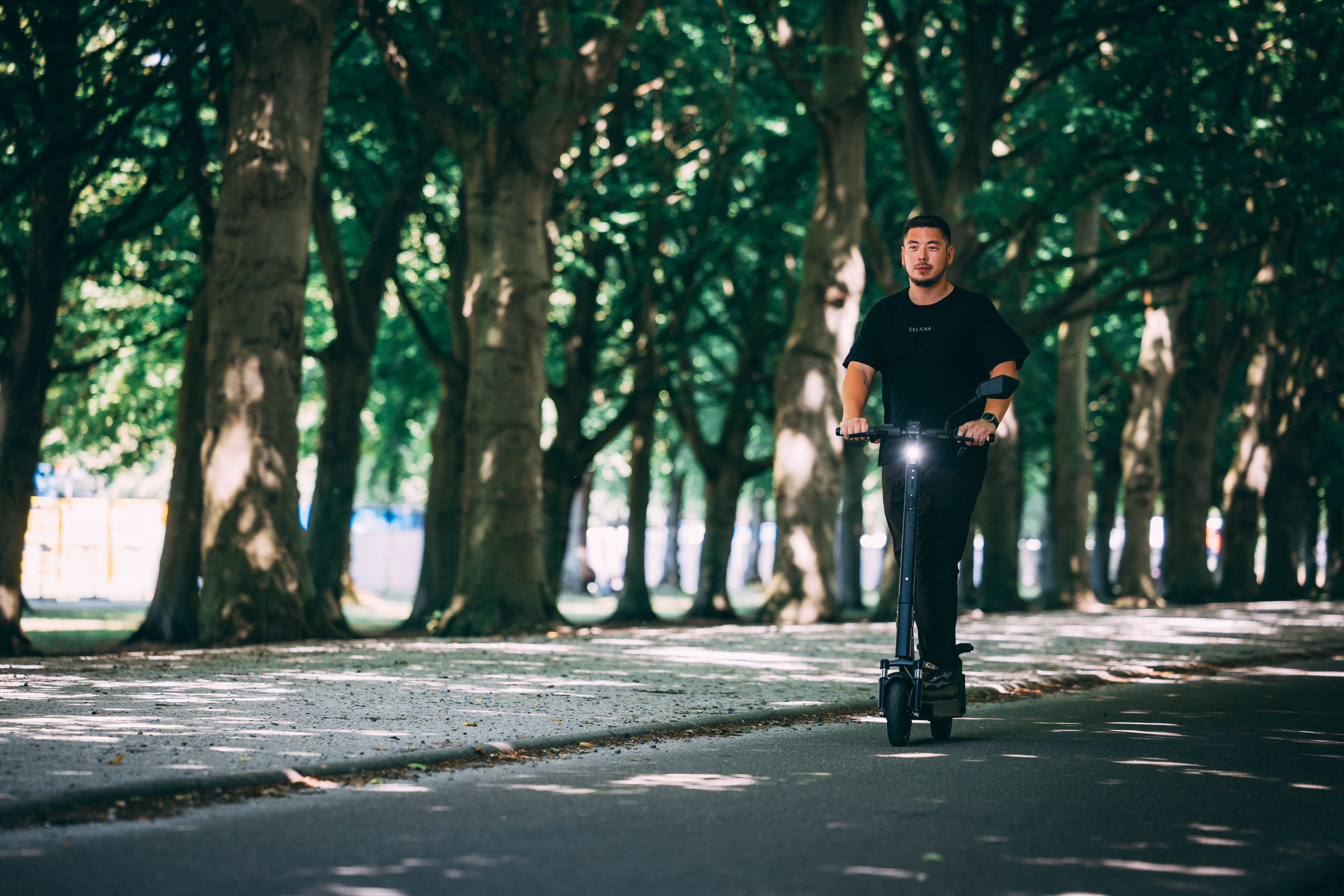 Rider on a SELANA Alpha down a long tree-lined avenue